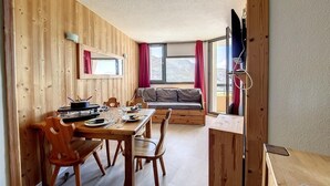 A wooden interior with a dining table, chairs, a sofa, and a TV mounted on a wooden stand. - 2nd floor, balcony, tv, ski locker, 24m², Les Menuires (Les Menuires)