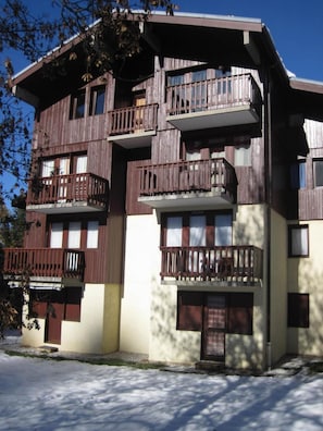 Un edificio de varios pisos con balcones de madera y ventanas amplias.