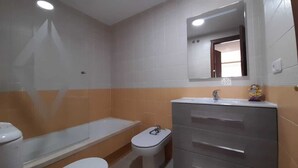 A bathroom with a toilet, bidet, and a sink with a mirror above it.