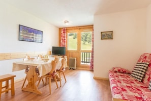 A cozy room with a dining table, chairs, a sofa, and a TV.