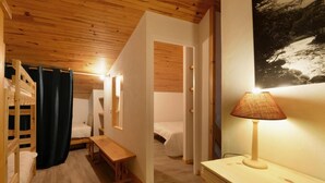 Et lille værelse med køjesenge, et skrivebord og en lampe.