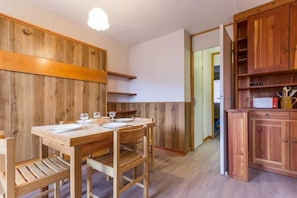 A wooden dining table with chairs, a wooden cabinet, and a light fixture.