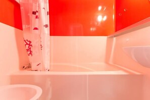 Ein Badezimmer mit einem weißen Waschbecken, einem roten Duschvorhang mit Graffiti und einer roten Wand.