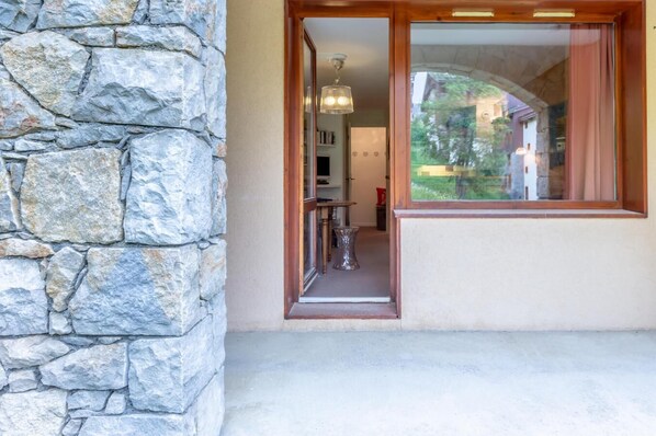 A stone wall, a wooden door, and a view through a window. - 5th floor, view mountain, terrace, ski locker, 21m², Valmorel (Valmorel)