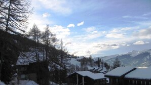 Un village de montagne enneigé, avec des bâtiments en bois et une piste de ski.