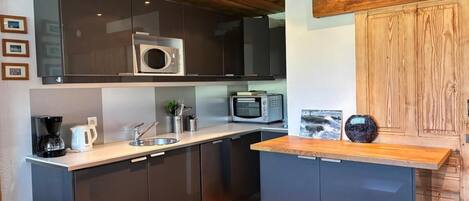 A modern kitchen with dark cabinets, a microwave, a toaster, and a coffee maker.