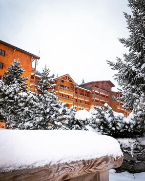 A multi-story wooden building with balconies, surrounded by snow-covered trees. - 70m from ski slopes, 3rd floor, view mountain, parking, tv, ski locker, 20m², Valfréjus (Valfréjus)