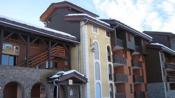 A multi-story building with a stone facade, wooden balconies, and a snow-covered roof. - 50m from ski slopes, 5th floor, balcony, tv, 28m², Montchavin La Plagne (Bellentre)