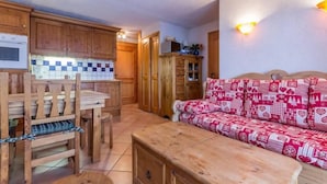 Une cuisine chaleureuse avec des meubles de rangement en bois, une table à manger et un canapé à motifs.