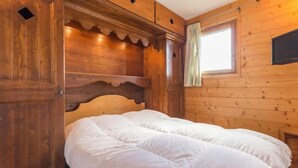 Une pièce en bois avec un lit, une fenêtre avec des rideaux et des murs en bois.
