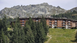 Un hôtel à plusieurs étages, doté de balcons, situé dans un cadre montagneux.