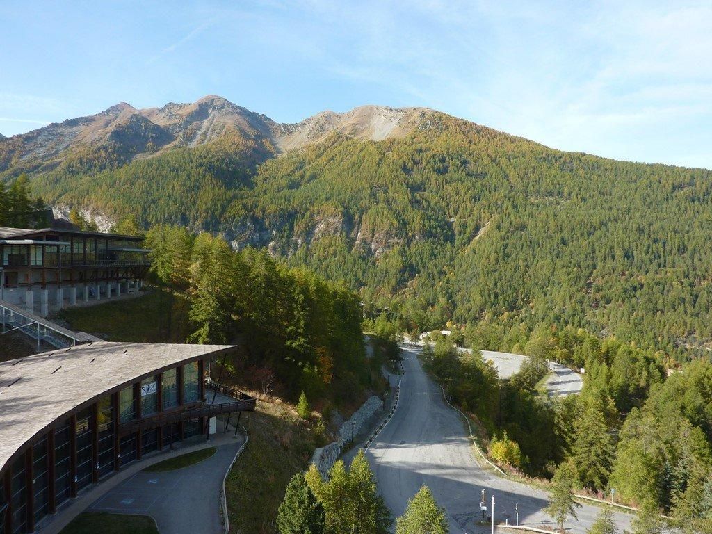 A building with a curved roof and a road leading to a mountainous area.