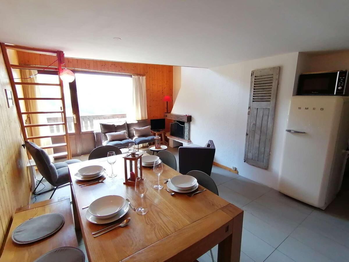 A dining area with a wooden table set for four, a television, and a kitchen area with a microwave and refrigerator.