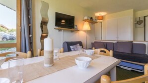 Ett mysigt rum med ett matbord, stolar, en soffa, en tv och en lampa.