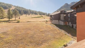 A building with a stone facade, multiple balconies, and a view of a mountainous landscape. - 50m from ski lifts, 2nd floor, balcony, parking, tv, 28m², Montgenèvre (Montgenèvre)