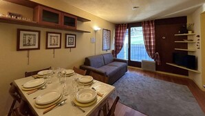 A dining area with a table set for four, a sofa, and a television on a stand. - Ski-in/ski-out & foot of the slopes, 1st floor, view ski slopes, parking, tv, 50m², Montgenèvre (Montgenèvre)