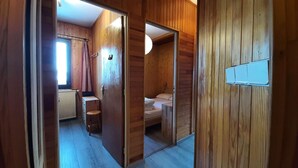 A wooden-paneled room with a bed, a small desk, and a chair. - 1st floor, view mountain, tv, 50m², Montgenèvre (Montgenèvre)