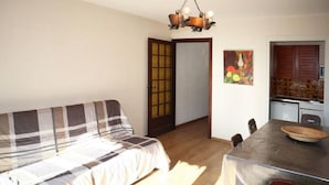 Une pièce confortable avec un canapé, une table à manger et des chaises, un coin cuisine et une porte donnant sur une autre pièce.