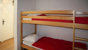 Un lit superposé à deux niveaux, chaque niveau étant équipé d’un matelas rouge et blanc.