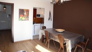 Un espace repas avec une table, des chaises et une cuisine en arrière-plan.