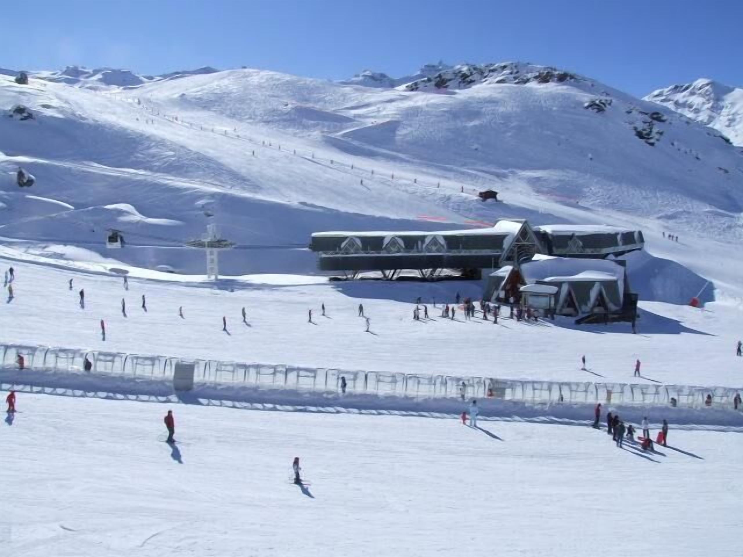 A ski resort with a chairlift, snow-covered slopes, and a lodge with a modern design.