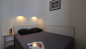 A small, neatly arranged bedroom with a single bed, a bedside table with books, and a framed picture on the wall. - Ski-in/ski-out & foot of the slopes, sauna, hammam, balcony, tv, 28m², Val Thorens (Val Thorens)