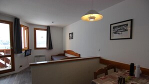 A small, cozy room with a bed, a table with a tablecloth, a hanging light fixture, and a framed picture on the wall. - Ski-in/ski-out & foot of the slopes, sauna, hammam, balcony, tv, 28m², Val Thorens (Val Thorens)