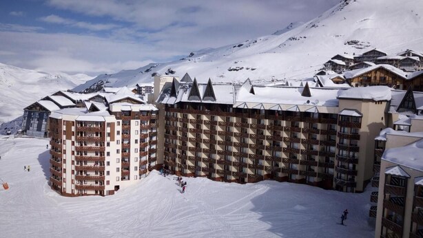 A snow-covered ski resort with multi-story buildings, ski slopes, and mountainous terrain. - Ski-in/ski-out & foot of the slopes, sauna, hammam, balcony, tv, 28m², Val Thorens (Val Thorens)