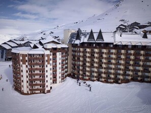 A snow-covered ski resort with multi-story buildings, ski slopes, and a mountainous backdrop. - Sauna, hammam, balcony, tv, 28m², Val Thorens (Val Thorens)