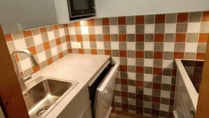 Una cocina compacta con microondas, lavaplatos y fregadero.