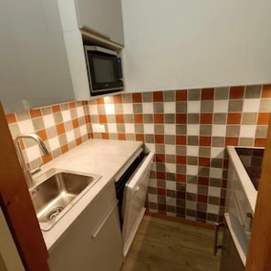 A compact kitchen with a microwave, a sink, and a dishwasher.
