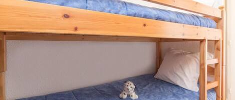 Un lit superposé avec un matelas bleu et un petit jouet en peluche sur le lit du bas.