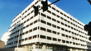 Un parcheggio multipiano con facciata bianca e diversi livelli di posti auto.