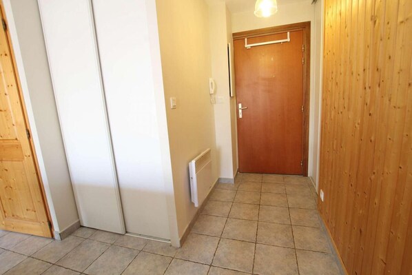 A hallway with a wooden door, a radiator, and a white wall. - 100m from ski slopes, 1st floor, balcony, parking, tv, 54m², Montgenèvre (Montgenèvre)