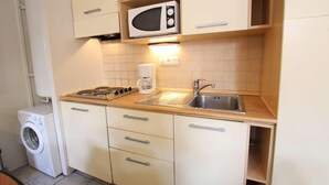 A compact kitchen with a microwave, stove, sink, and a washing machine. - 100m from ski slopes, 1st floor, balcony, parking, tv, 54m², Montgenèvre (Montgenèvre)