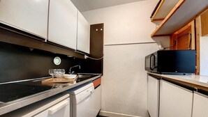 A compact kitchen with a microwave, stove, and dishwasher. - 50m from ski slopes, 2nd floor, balcony, tv, 38m², Les Menuires (Les Menuires)