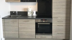 A modern kitchen with light wood cabinets, a black microwave, a Bosch coffee maker, and a Bosch oven. - 150m from ski slopes, Ground floor, balcony, 29m², Val Thorens (Val Thorens)