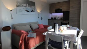 A modern living room with a sofa, a dining table, and a kitchen area. - 150m from ski slopes, Ground floor, balcony, 29m², Val Thorens (Val Thorens)