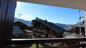 A traditional chalet-style building with a balcony, set against a backdrop of mountains and clear skies. - 150m from ski slopes, Ground floor, balcony, 29m², Val Thorens (Val Thorens)