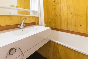 Un baño con un lavamanos blanco, un espejo y paneles de madera.