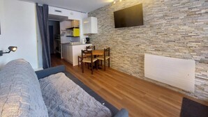 Un espace de vie compact comprenant un coin cuisine, un coin repas et un lit confortable.