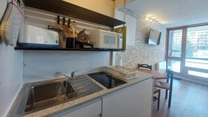 Une cuisine moderne équipée d’un évier à deux bacs, d’un four à micro-ondes et d’un four encastré. Un coin repas avec une table et des chaises est également disponible.