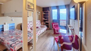 Ein gemütliches Zimmer mit Bett, Sofa, Sessel, einem kleinen Tisch und einem Balkon mit Blick.