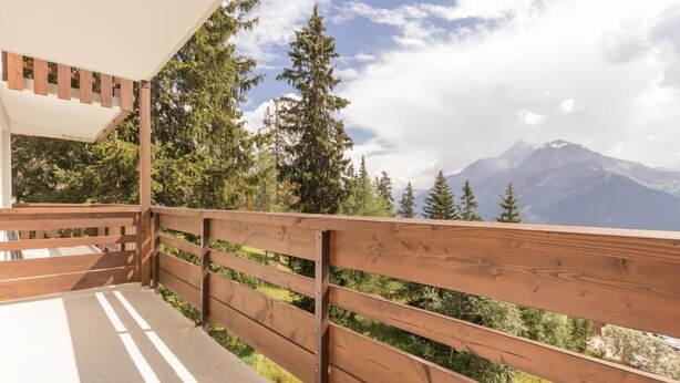 Ein Holzbalkon mit Blick auf ein Gebirge.