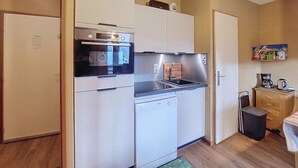 Eine kleine Küche mit Kühlschrank, Backofen, Mikrowelle und Geschirrspüler.