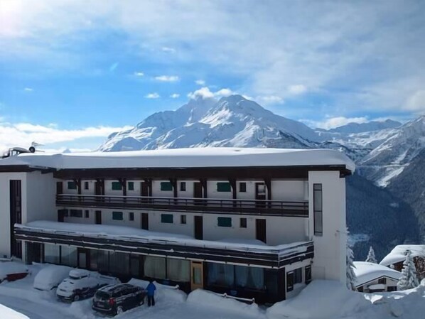 A modern hotel with a two-story structure, large windows, and a view of snow-covered mountains. - 200m from shops, Ground floor, view valley, balcony, tv, 43m², La Rosière (La Rosière Montvalezan)