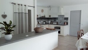 A modern kitchen with white cabinets, a grey countertop, and a dining area with a table and chairs. - Villa Pampérigouste - air conditioning and swimming pool (SOLLIES TOUCAS)
