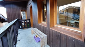 Une terrasse en bois avec un banc et une fenêtre donnant sur un immeuble.