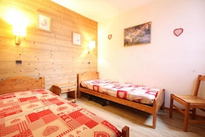 A cozy room with two wooden beds, a nightstand, a chair, and a painting on the wall. - 100m from ski slopes, 2nd floor, view mountain, balcony, tv, ski locker, 41m², Montchavin La Plagne (Bellentre)