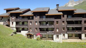 A multi-story hotel with balconies, stone facade, and a mountainous backdrop. - 10m from ski slopes, 3rd floor, balcony, 43m², Méribel-Mottaret (Méribel - Les Allues)